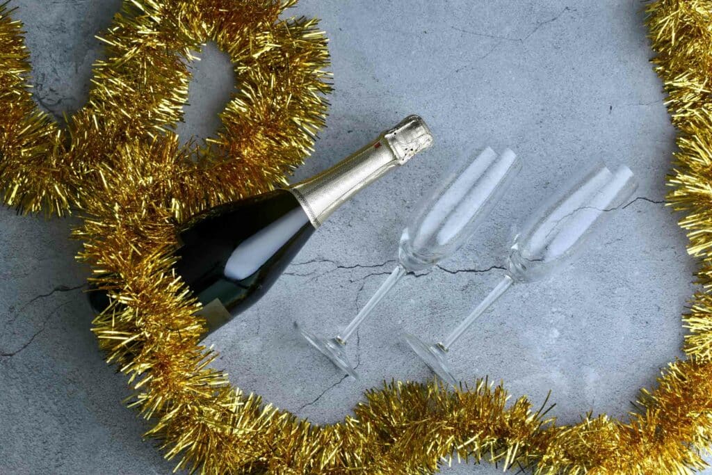 guirlande qui entoure une bouteille de champagne et deux coupes